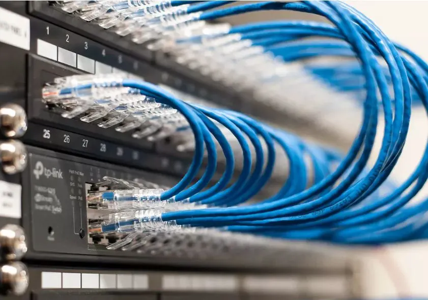 Blue Cat6 patch cords connected to a patch panel in a network rack