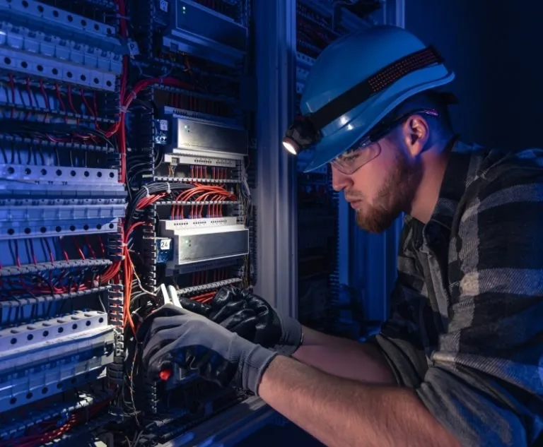 Network cabling technician wearing a helmet working inside a cabling cabinet